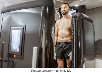 Man taking cryotherapy treatment, standing at the capsule door at a Spa salon