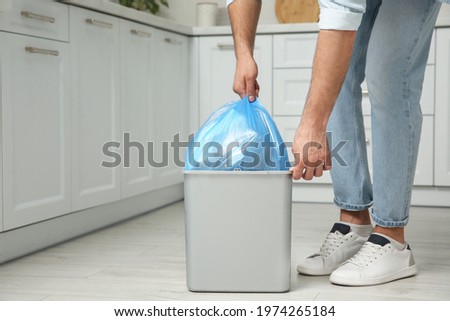 Man taking garbage bag out of bin at home, closeup