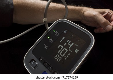 Man Taking His Own Blood Pressure With A Digital Home Blood Pressure Monitor