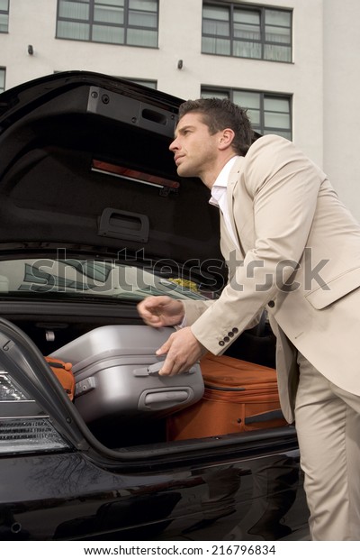 Man taking a luggage\
from a car trunk