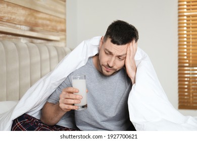 Man Taking Medicine For Hangover In Bedroom At Home