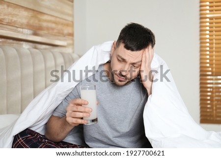 Man taking medicine for hangover in bedroom at home