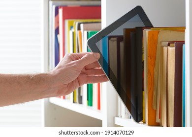 Man taking modern ebook reader from a bookshelf. 