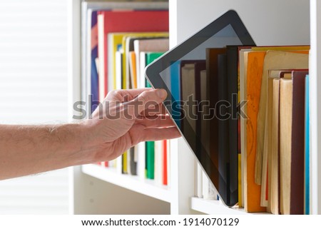 Man taking modern ebook reader from a bookshelf. 