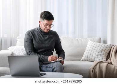 Man taking notes during online lesson at table indoors, space for text. Self-study