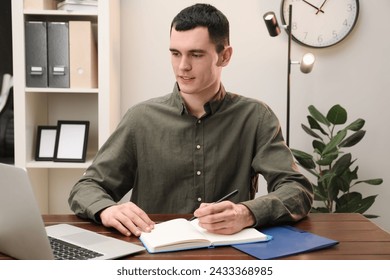 Man taking notes at wooden table in office