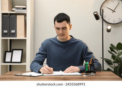 Man taking notes at wooden table in office