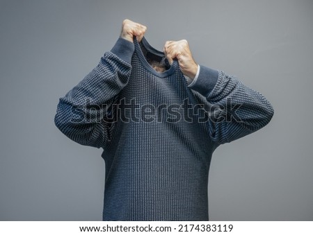 man taking off sweater, isolated on gray background