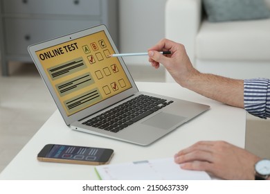 Man Taking Online Test On Laptop At Desk Indoors, Closeup