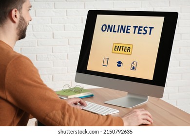 Man Taking Online Test On Computer At Desk Indoors