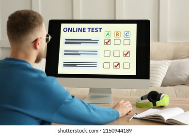 Man Taking Online Test On Computer At Desk Indoors