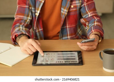 Man Taking Online Test On Tablet At Desk Indoors, Closeup