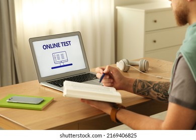 Man Taking Online Test On Laptop At Desk Indoors, Closeup