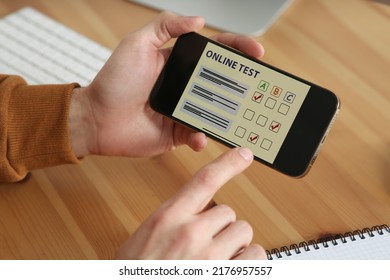 Man Taking Online Test On Smartphone At Desk, Closeup