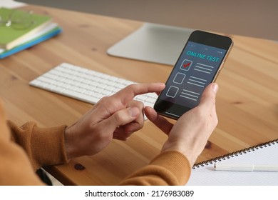 Man Taking Online Test On Smartphone At Desk, Closeup