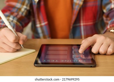 Man Taking Online Test On Tablet At Desk, Closeup