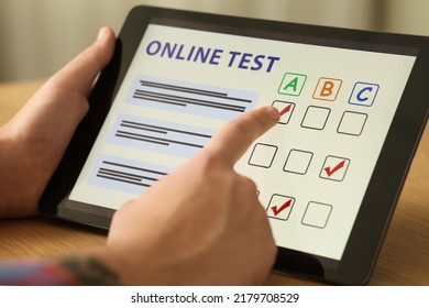 Man Taking Online Test On Tablet At Desk Indoors, Closeup