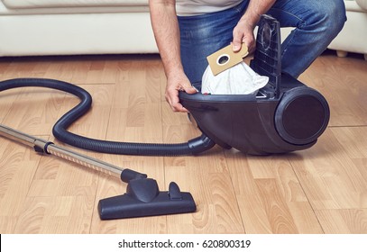 Man taking out a full dust bag from a vacuum cleaner                               