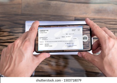 Man Taking Photo Of Cheque To Make Remote Deposit In Bank