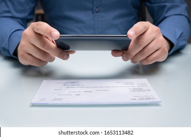 Man Taking Photo Of Cheque To Make Remote Deposit In Bank - Shutterstock ID 1653113482