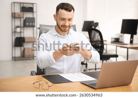 Man taking photo of document using scanning app on smartphone at desk in office