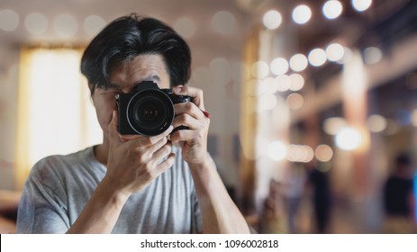 a man taking photography by digital mirrorless camera, with Bokeh light background