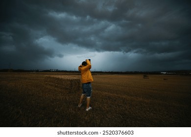 Man taking photos of a storm cloud over field, tornadic supercell. - Powered by Shutterstock