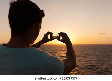 Man Taking Picture Of Beautiful Sunset Over Sea