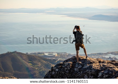 A man is taking a picture on top of the table mountain