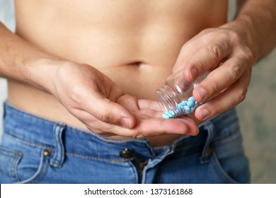 Man Taking Pills, Bottle With Blue Tablets In Male Hands Close Up. Guy In Unzipped Jeans With Naked Torso, Concept Of Viagra, Drugs For Digestion, Medication For Erection Before Sex, Sleeping Pill