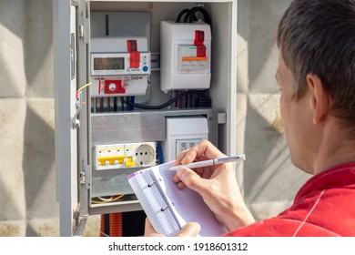 Man taking readings of an electric meter - Shutterstock ID 1918601312