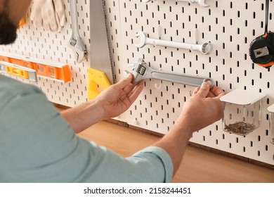 Man Taking Screw-wrench From Pegboard In Workshop, Closeup