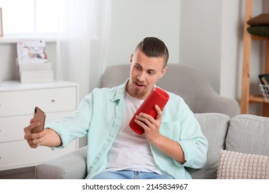 Man Taking Selfie With Wireless Portable Speaker On Sofa In Room