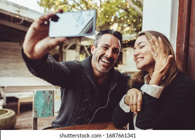 Man taking selfie with woman showing her engagement ring while sitting at coffee shop. Loving couple making selfie with the engagement ring. - Powered by Shutterstock