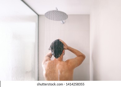 Man taking a shower washing hair with shampoo product under water falling from luxury rain shower head. Morning routine luxury hotel lifestyle guy showering. body care hygiene.