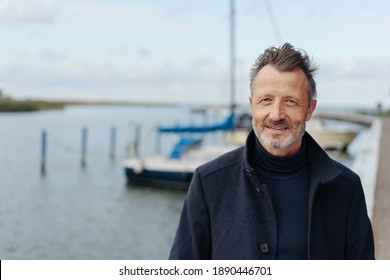 Man taking a stroll on a waterfront promenade in a warm overcoat on a cold autumn day in a close up portrait - Powered by Shutterstock