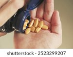 A man taking Vitamin B Complex tablets out of a bottle. Close up.