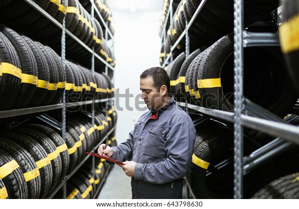 Man taking wheel\
from shelves in warehouse. 
