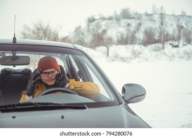 man talking by phone while sitting in the car in winter day