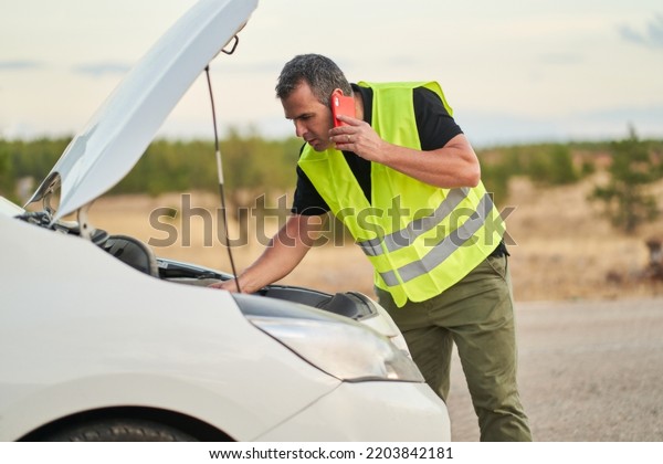 a man
talking to the car insurance company to request travel assistance
for a breakdown while driving his
car