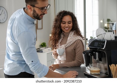 Man talking with colleague while using modern coffee machine in office