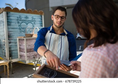 Man talking to coworker writing menu while standing by food truck - Powered by Shutterstock