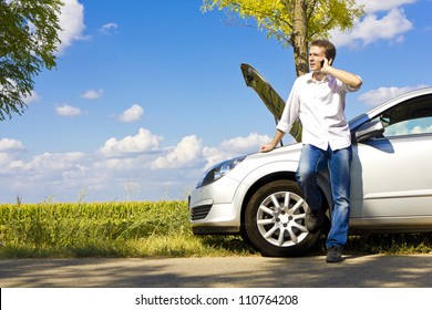 Man Talking On A Cell Phone By A Broken Car