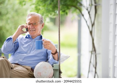 Man Talking On Cell Phone In Porch Swing