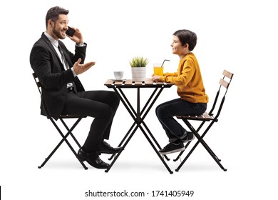 Man Talking On A Mobile Phone And Sitting At A Table With A Child Isolated On White Background