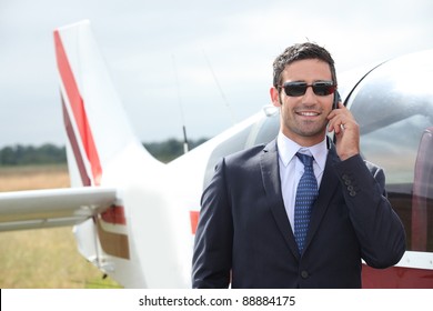 Man talking on a mobile phone next to a private plane