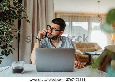 Man talking on phone, using laptop, and thinking during a home office work session