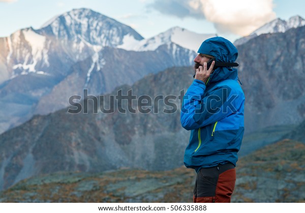 man talking\
on a satellite phone in the\
mountains