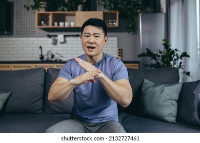 Man Talking On Webcam, Angry Gesturing With Hands, Asian Looking At Camera, Online Call Sitting On Sofa At Home