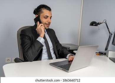 A man talking to a phone in front of a computer